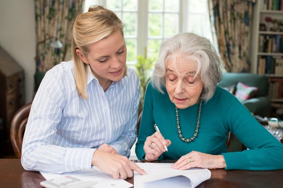 Woman helping an elder with paperwork
